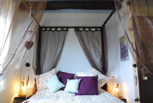 1 dormitorio con cama con dosel y almohadas moradas y blancas en Torre Viladot, en Solsona