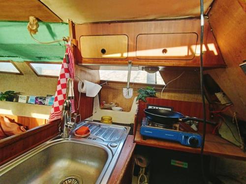 a small kitchen with a sink and a stove at Relax on the canals Cozy Sailboat for 3 people in Groningen