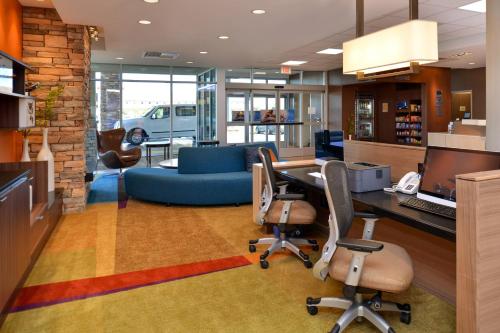 Fairfield Inn & Suites by Marriott Sacramento Airport Woodland في وودلاند: مكتب به أريكة زرقاء ومكتب وكراسي