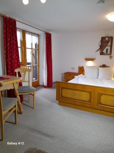 a bedroom with a bed and a table and chairs at Alpenpension Ettlerlehen in Ramsau
