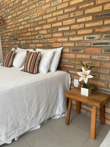 a bedroom with a brick wall and a bed and a table at Chalés Solar do Patacho in Pôrto de Pedras