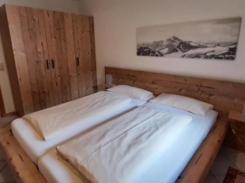 拜里施采爾的住宿－Supreme Apartment in Bayrischzell with Infrared Sauna, Garden，卧室配有一张床,墙上挂着一幅画