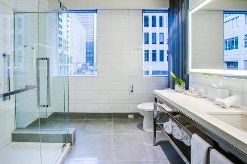 Renaissance Montreal Downtown Hotel في مونتريال: حمام مع دش زجاجي ومرحاض