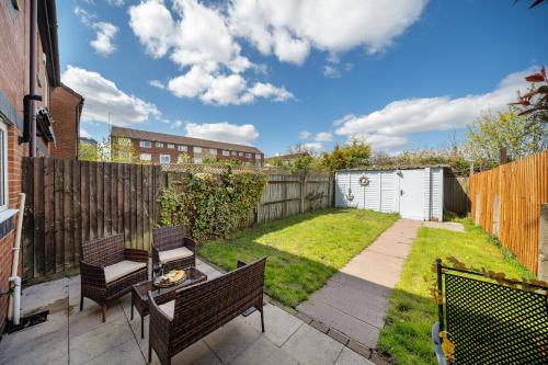 a backyard with two chairs and a table and a fence at Stylish 3 bed house, large garden, Parking, WiFi - Esho Stays in Coventry