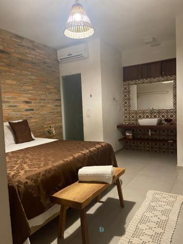 a bedroom with a bed and a bench and a mirror at Chalés Solar do Patacho in Pôrto de Pedras