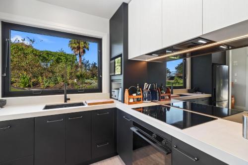 a kitchen with black cabinets and a large window at Sanctuary Ridge in Tauranga