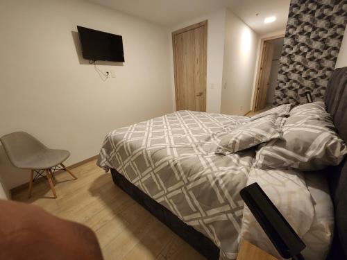 a bedroom with a bed and a chair and a television at Suite departamento de lujo sector la Carolina in Quito