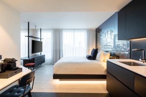 Residence Inn Ghent by Marriott في خنت: غرفة نوم بسرير ومطبخ مع حوض