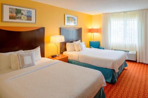 a hotel room with two beds and yellow walls at Fairfield Inn Joplin in Joplin