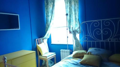 Dormitorio azul con cama y ventana en Apartments on Italyanskaya, en San Petersburgo