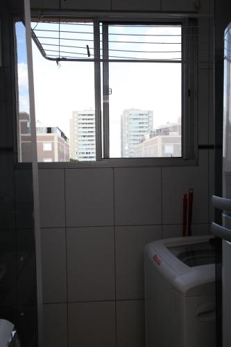 a bathroom with a window and a toilet and a sink at Apartamento Aeroporto/ Uniube in Uberaba