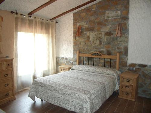 um quarto com uma cama e uma parede de pedra em Las Casitas Del Bodegon em El Gasco