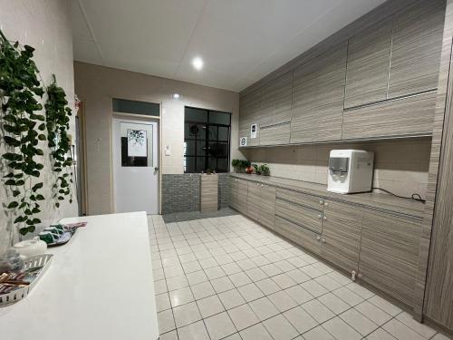 a kitchen with brown cabinets and a white tile floor at Joyful homestay Miri in Miri