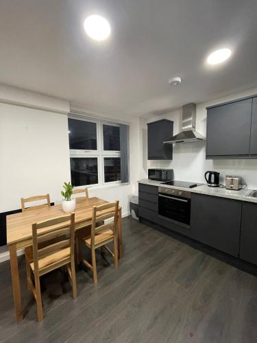 a kitchen with a wooden table and a dining room at Charming Modern Apartment near London Heathrow in Feltham