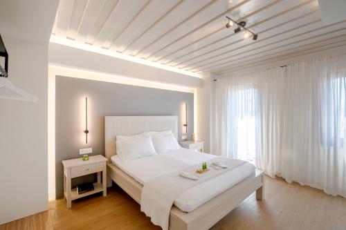 a white bedroom with a large bed and a window at Hanim Boutique Hotel in Chania