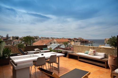 een patio met een tafel en stoelen en de oceaan bij Hanim Boutique Hotel in Chania