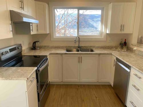 a kitchen with white cabinets and a sink and a window at Avo-Sa Orchard in Lake Country