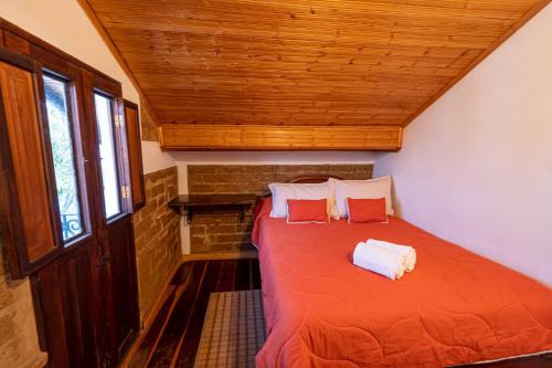 a bedroom with a bed with orange sheets and pillows at Hotel Casa Elemento Villa de Leyva in Villa de Leyva