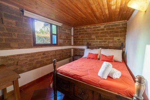 Hotel Casa Elemento Villa de Leyva في فيلا دي ليفا: غرفة نوم مع سرير وملاءات حمراء ونافذة