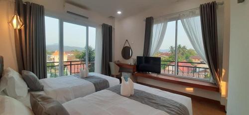 a hotel room with two beds and a large window at VangVieng Crystal Boutique Hotel in Vang Vieng