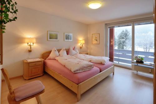 um quarto com uma cama e uma grande janela em Apartment Skyline 108 em St. Moritz