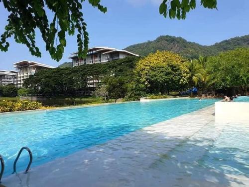 a large swimming pool with a resort in the background at Pico De Loro Hamilo Coast beach and Country Club - Myna B One Bedroom in Cutad