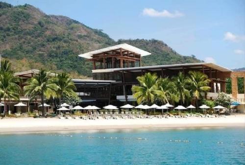 a resort on the beach with chairs and umbrellas at Pico De Loro Hamilo Coast beach and Country Club - Myna B One Bedroom in Cutad
