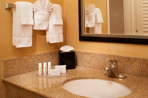 a bathroom sink with towels and a mirror at Courtyard by Marriott Chicago Naperville in Naperville