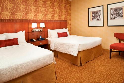 a hotel room with two beds and a chair at Courtyard by Marriott Chicago Naperville in Naperville