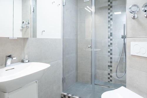 La salle de bains blanche est pourvue d'une douche et d'un lavabo. dans l'établissement Andreas-Dirks-Str-1-2-OG-Wohnung-207, à Westerland