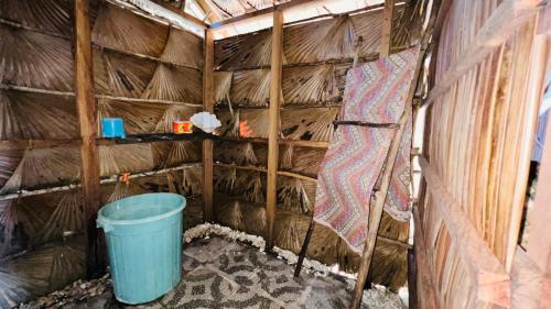 um quarto com um balde numa cabana de palha em Kamar Raja GuestHouse em Selpele