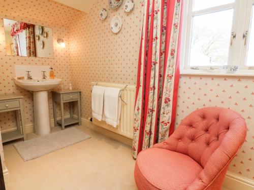 a bathroom with a red chair and a sink at The Garden Rooms Lawkland in Austwick