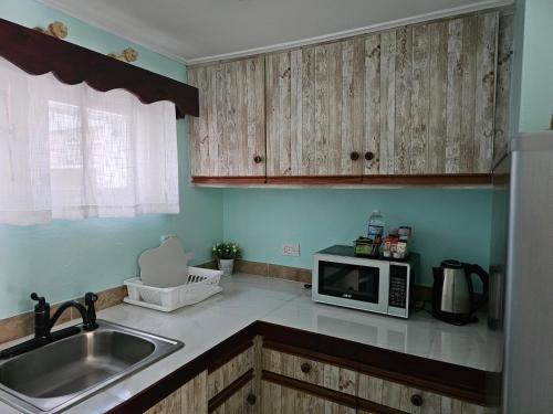 a kitchen with a sink and a microwave at Memories by the Shore in Negril