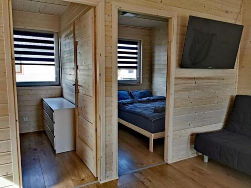 um pequeno quarto com uma cama e uma televisão em Cozy cottages in a family holiday resort, Jezierzany em Jezierzany