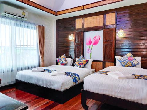 1 dormitorio con 2 camas y una flor en la pared en Nan Bluesky Resort and Spa, en Nan