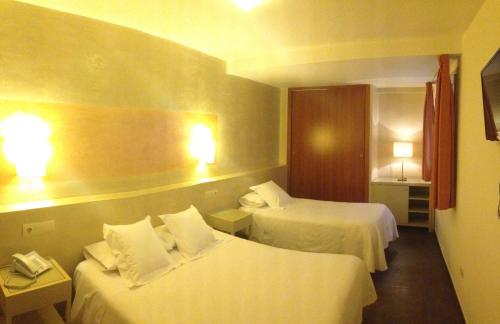 a hotel room with two beds and two lamps at Hotel Carmen in Roses