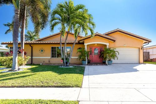 a house with palm trees in front of it at South Florida Spacious Oasis 4BR Retreat with 2 King Beds, Amazing Pool, near Beaches in Deerfield Beach
