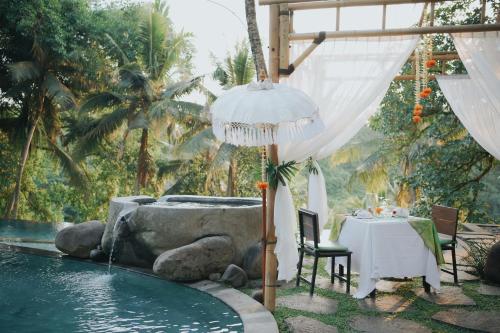 a table and an umbrella next to a swimming pool at Bucu View Resort in Ubud