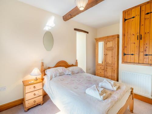 1 dormitorio con 1 cama grande y armario de madera en Billy Croft Cottage, en Knock