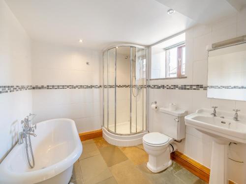 a bathroom with a toilet and a tub and a sink at Billy Croft Cottage in Knock