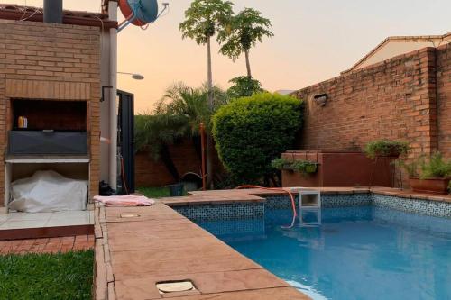 a swimming pool in a backyard with a brick wall at Casa en condominio a 3 minutos del Aeropuerto in Luque