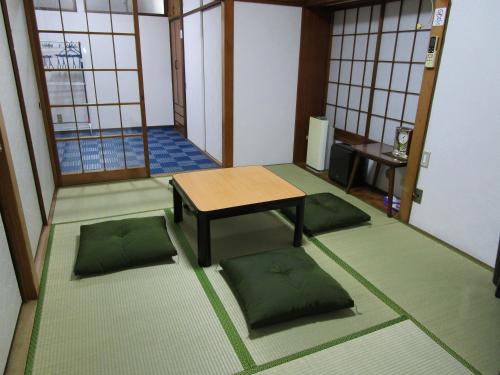 池袋駅まで徒歩15分 畳の家 في طوكيو: غرفة مع طاولة وبعض الوسائد على الأرض