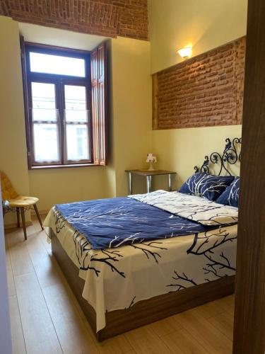 a bedroom with a bed with blue sheets and a window at Historic Apartments "1868 Tbilisi" Best Location in Tbilisi City