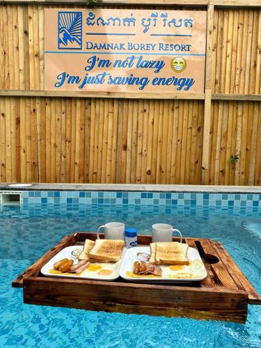 two plates of food on a tray in a swimming pool at Damnak Borey Resort in Kampot