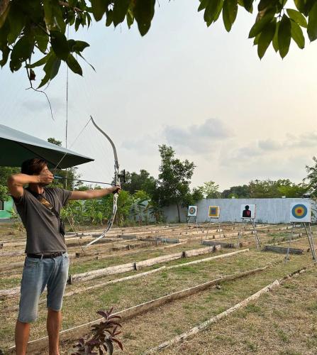 a man holding a bow and arrow in a field at Damnak Borey Resort in Kampot