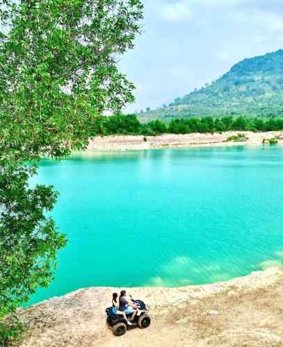 two people riding a four wheeler by a lake at Damnak Borey Resort in Kampot