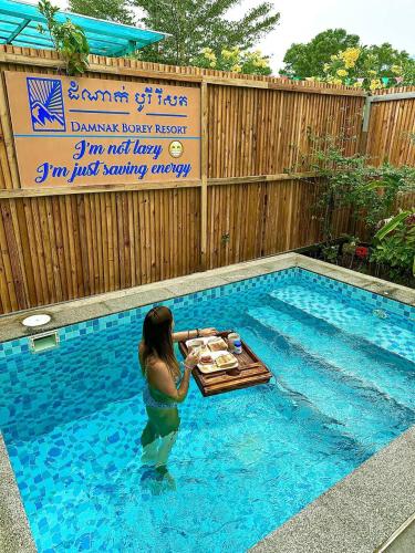a woman standing in a pool with a table in a swimming pool at Damnak Borey Resort in Kampot
