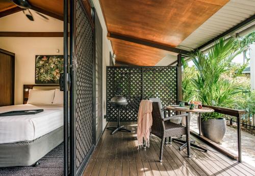 a bedroom with a bed and a table on a deck at Palms City Resort in Darwin