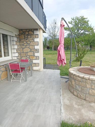 a patio with a table and a pink umbrella at La Clematite d'Olt in Saint-Côme-dʼOlt