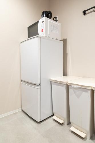 a white refrigerator with a microwave on top of it at Shinosaka private house for 16ppl in Osaka